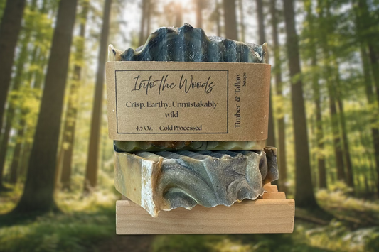 Two bars of soap on a wooden stand with a 'Into the Woods' label against a forest background.