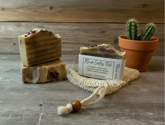 Two bars of soap and a small potted cactus on a wooden surface.