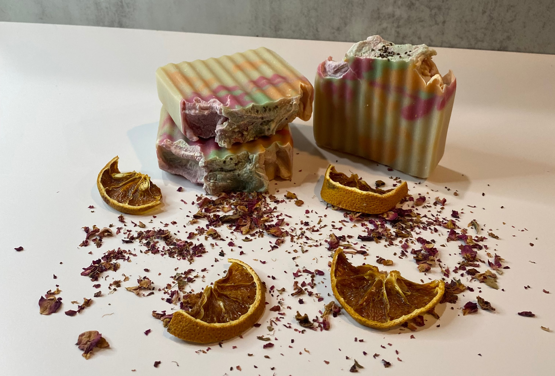 Two rectangular soap bars with decorative designs on a white surface with dried oranges and red flowers