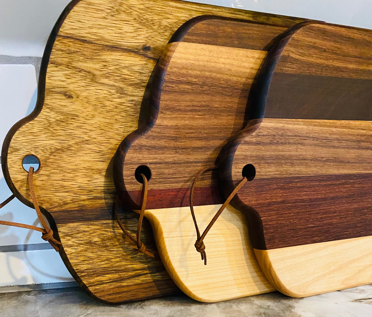 Three wooden cutting boards with different wood grain patterns on a marble surface.