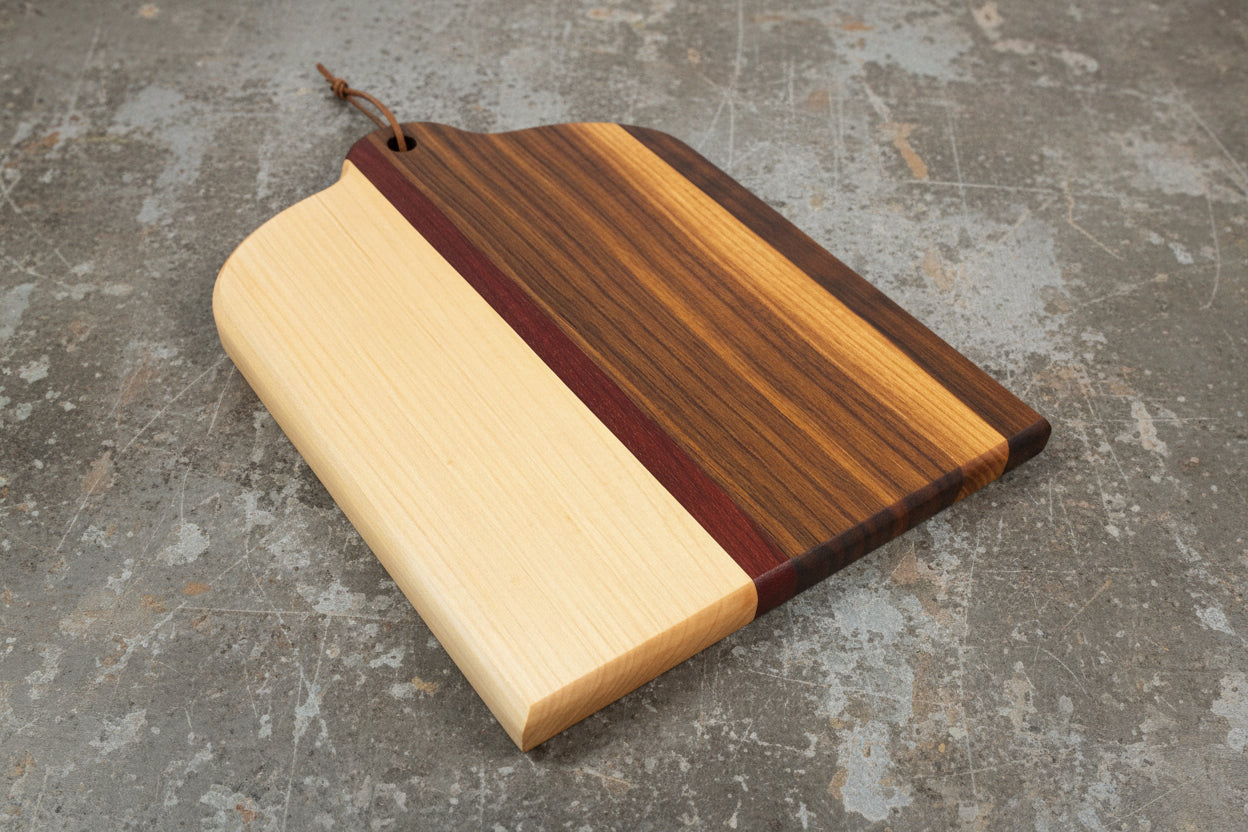 Wooden cutting board with multicolored stripes on a concrete surface
