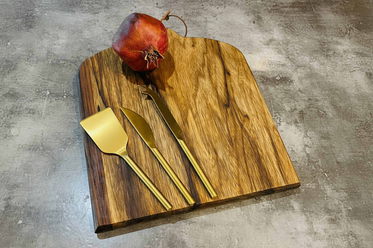 Wooden cutting board with a pomegranate, knife, and spatula on a concrete surface