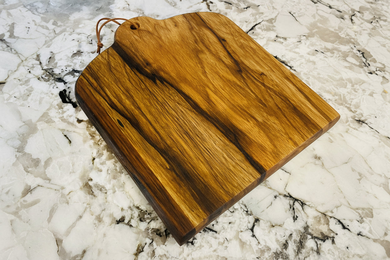 Black Limba cutting board on a granite surface
