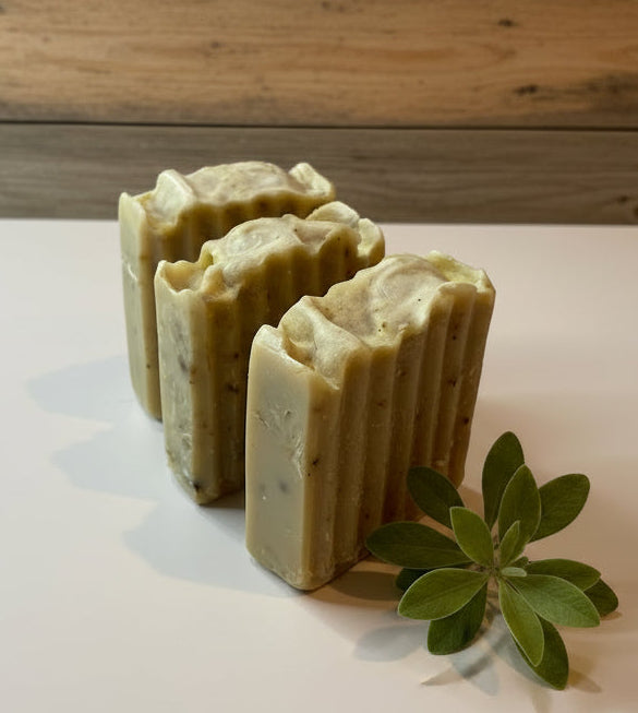 Three bars of soap with a green leaf on a light surface and wooden background