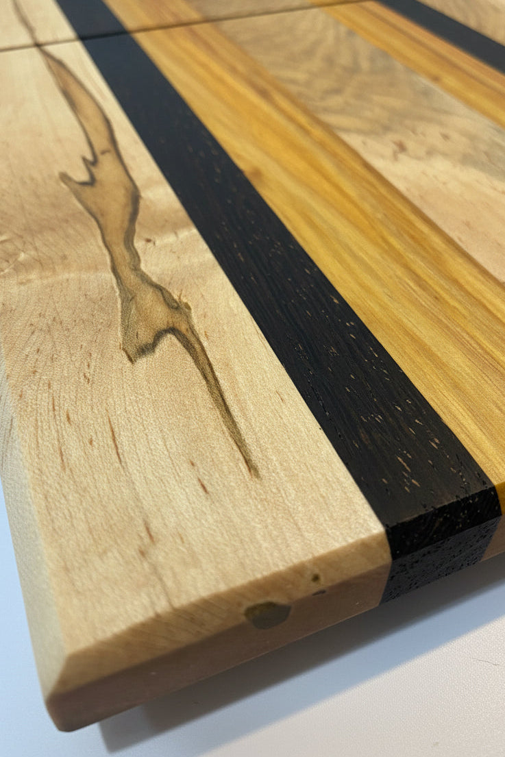 Wooden cutting board with black band and engraved design on a white background