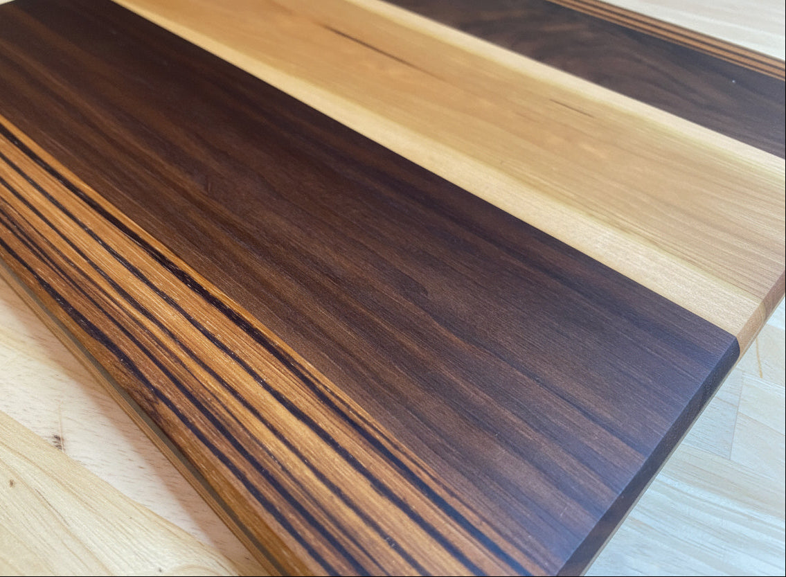 Walnut_Maple_Zebra cutting board on a wood surface